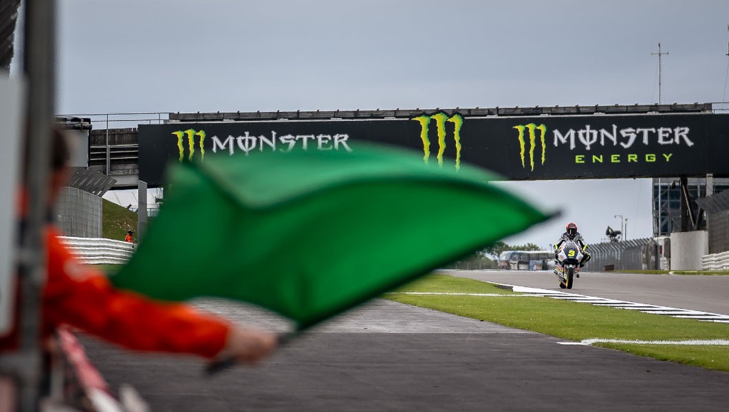 Auf dem Bild wird eine grüne Flagge an der Motorrad-Rennstrecke geschwenkt.