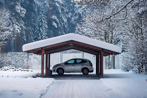 Das Bild zeigt ein Auto unter einem verschneiten Carport.